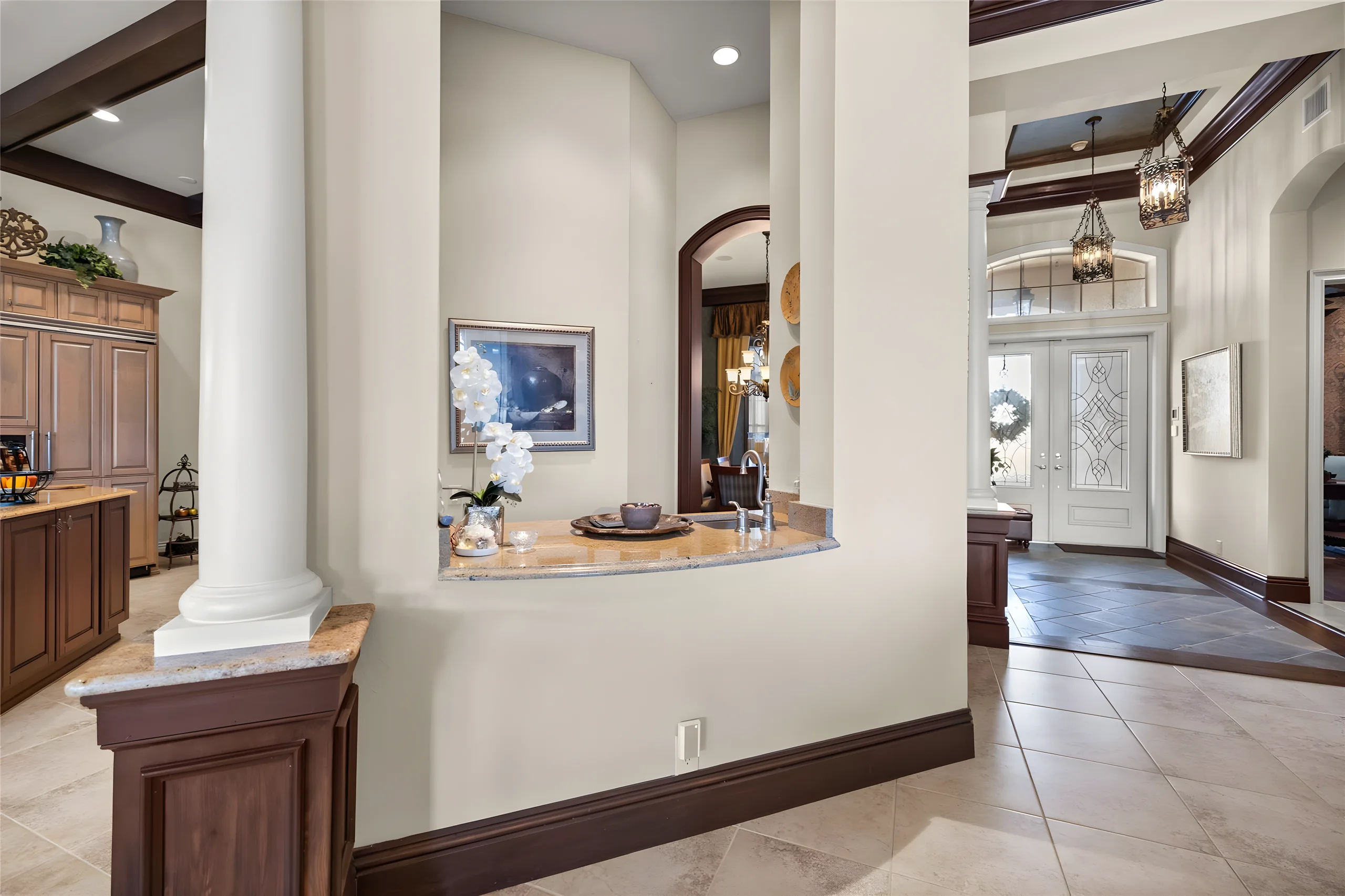 Wet bar counter seen from the hall, with the foyer and the front door beyond