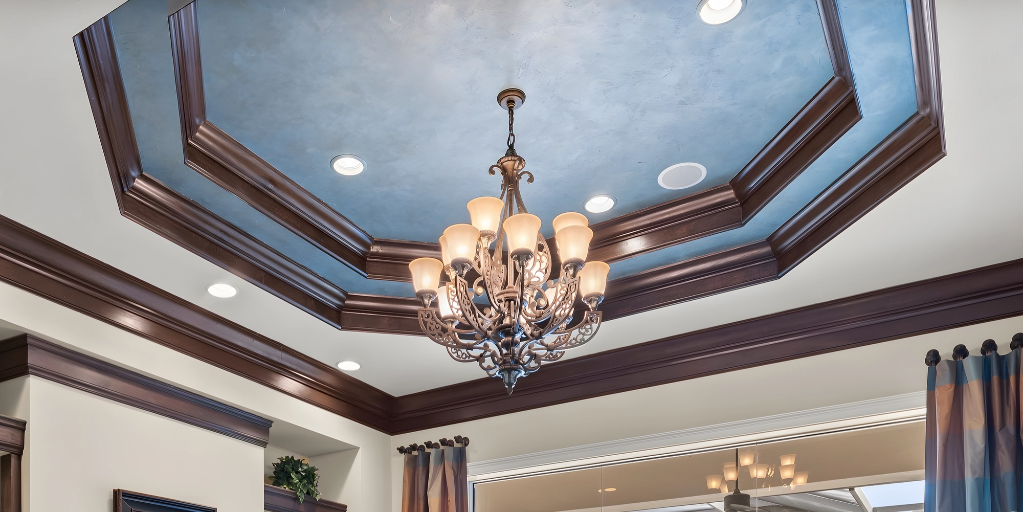 The formal living room's octagonal tray ceiling, painted blue, with tiers of dark crown molding and a chandelier