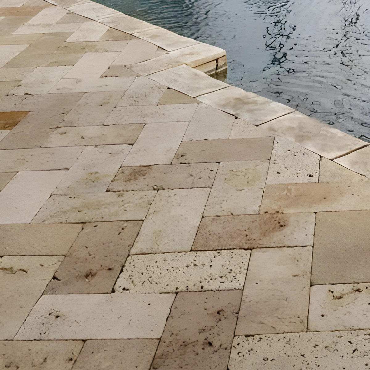Travertine pavers in a mixed pattern at the edge of the pool