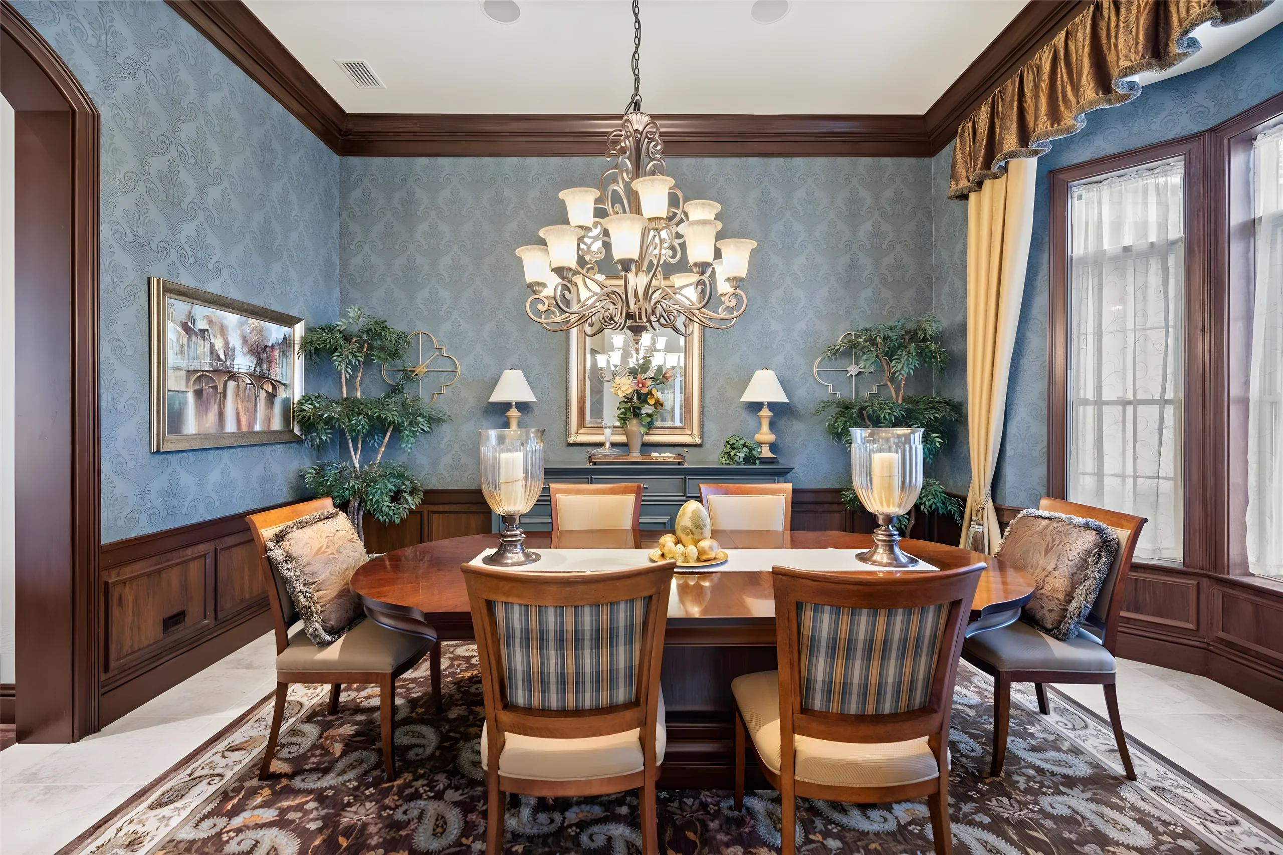 Formal dining room with blue damask walls, dark wood wainscoting, a crystal chandelier and a table for six