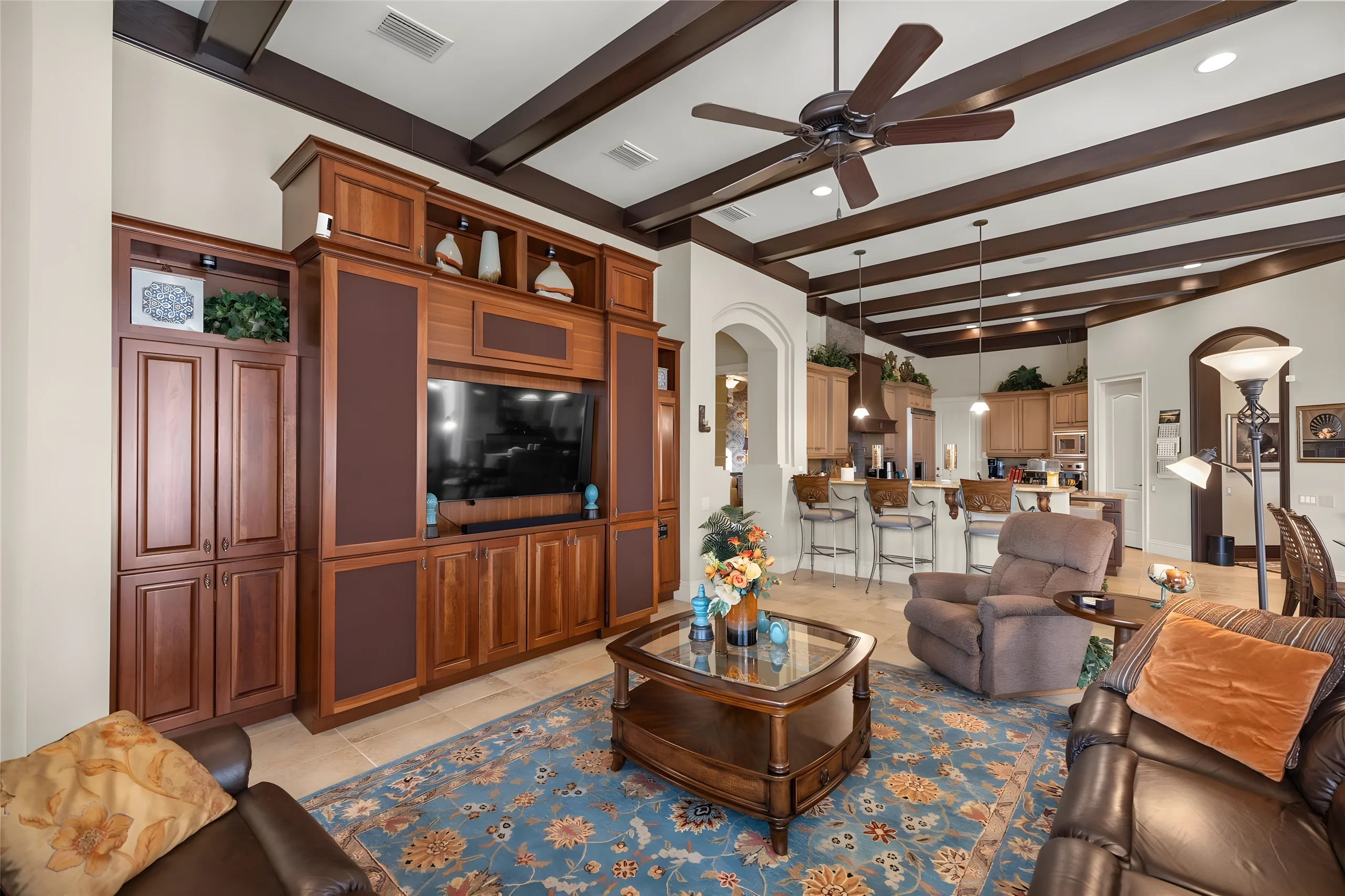 Family room with a beamed ceiling and a built-in wood entertainment center, open to the kitchen