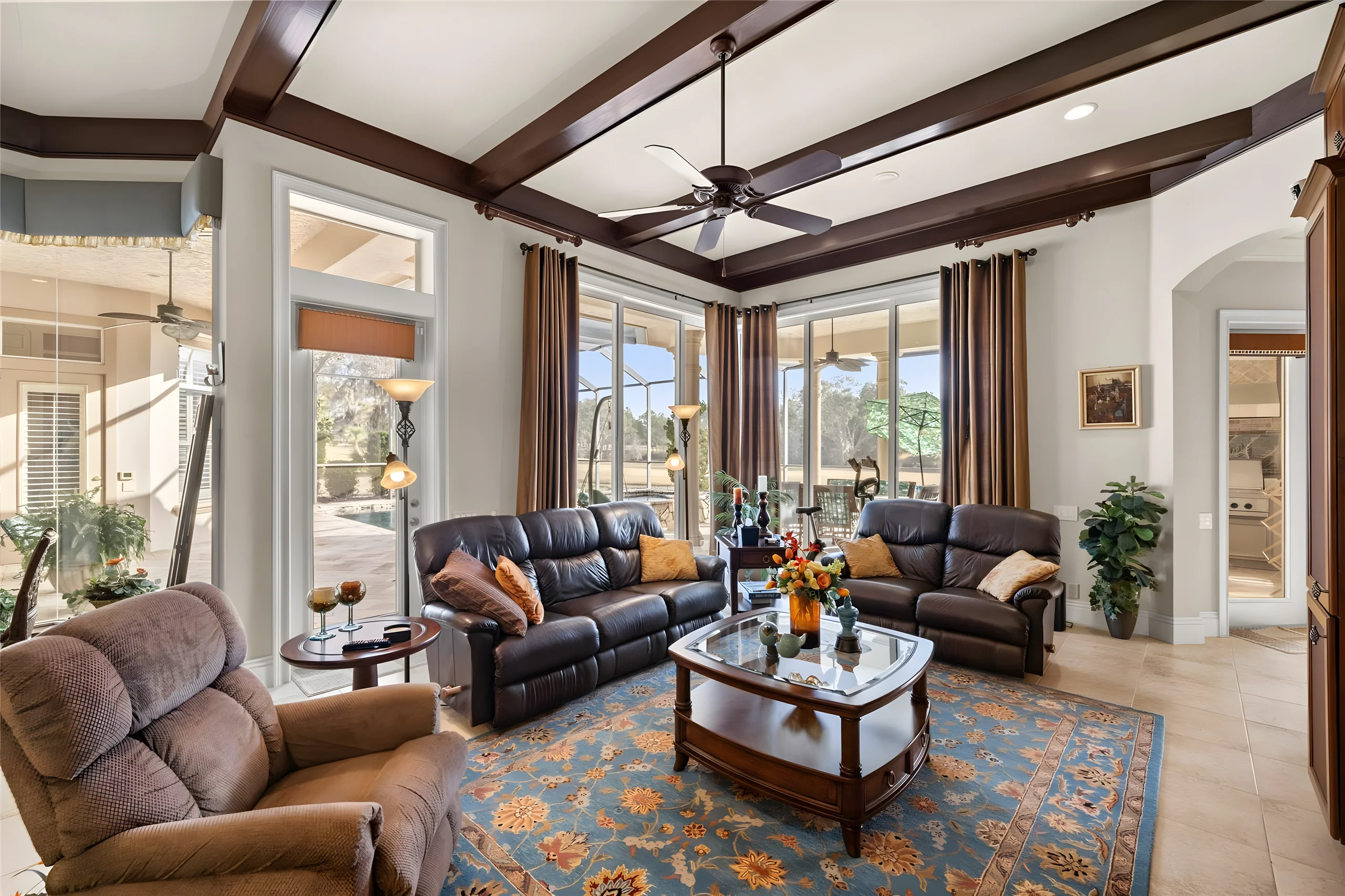Family room with a beamed ceiling and tall windows to the lanai
