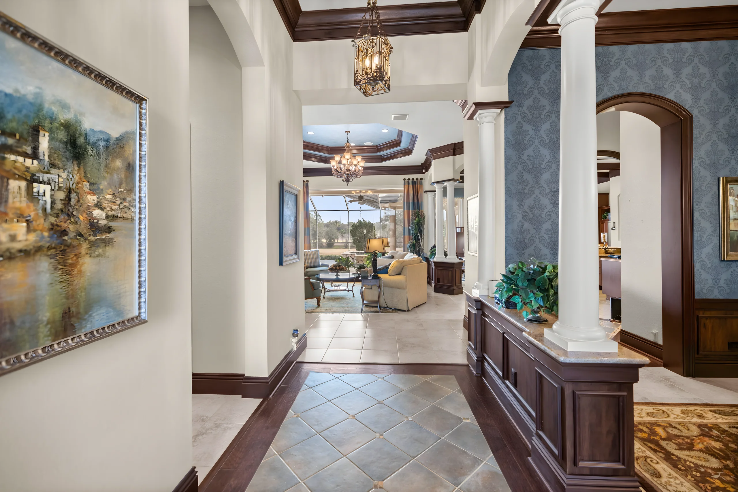 Foyer with a slate tile floor and columns, looking down the hall to the family room and the lanai