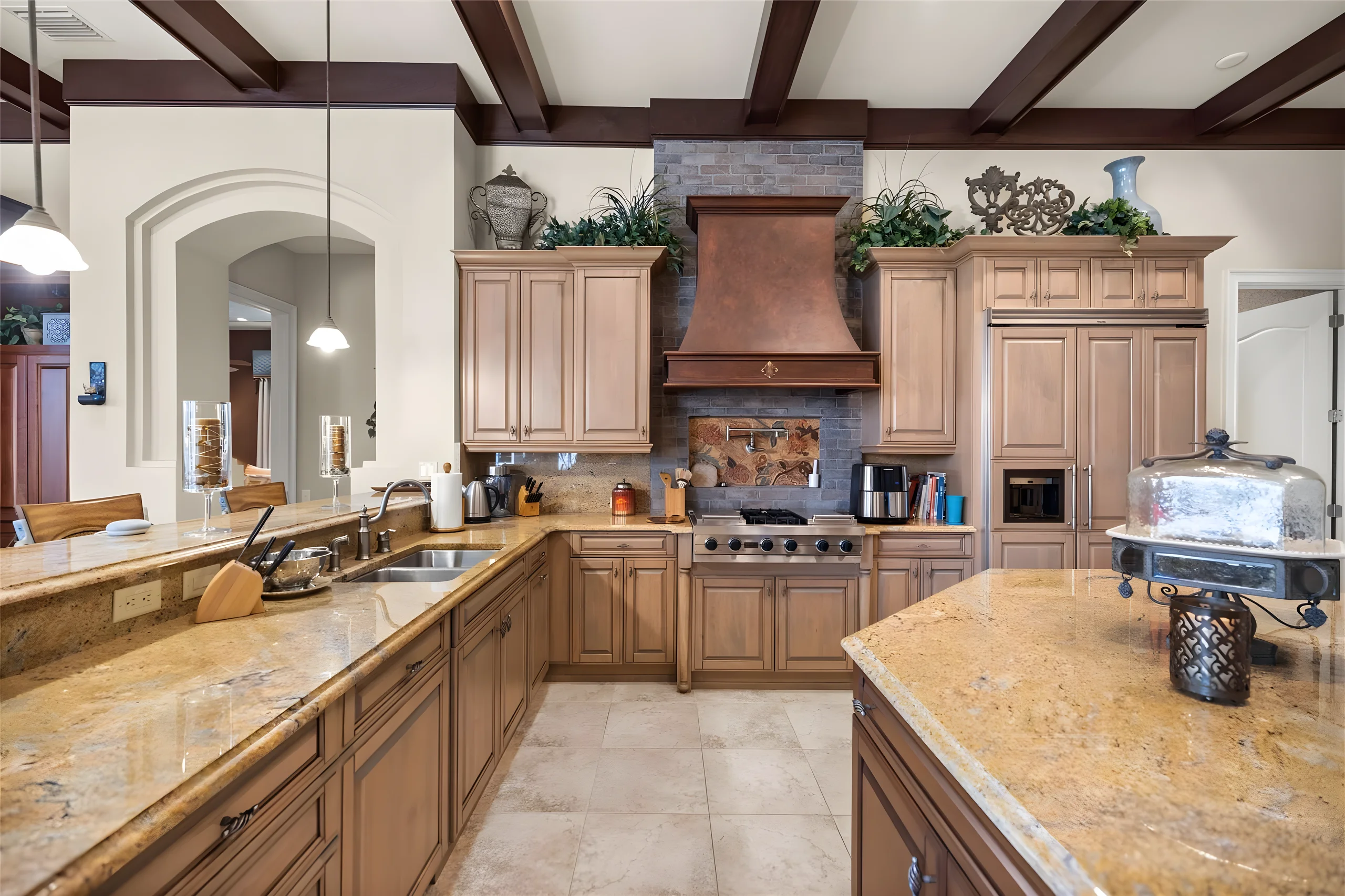Kitchen with a copper range hood over a gas cooktop, granite counters and an island