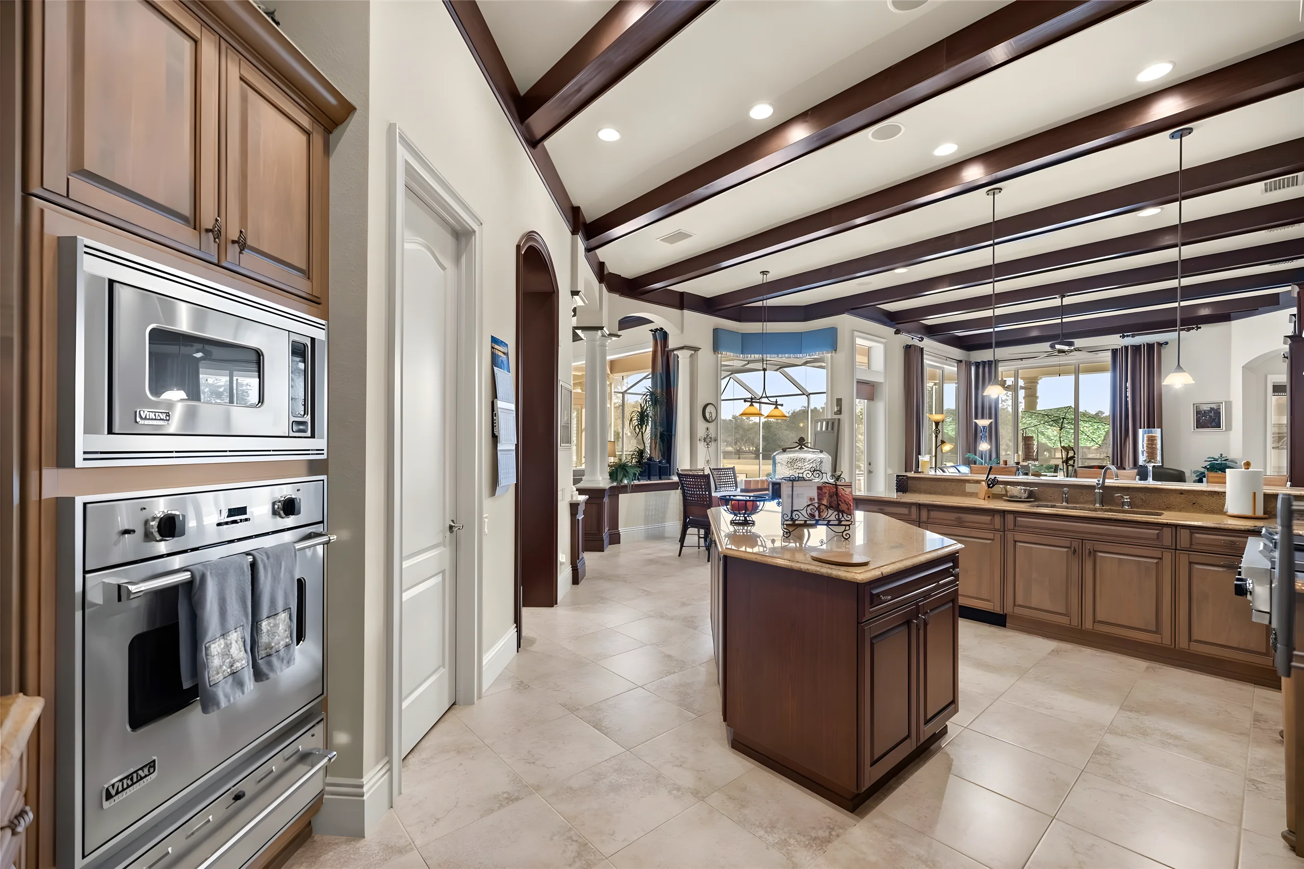 Kitchen from the double wall ovens, looking past the island to the breakfast area and the lanai