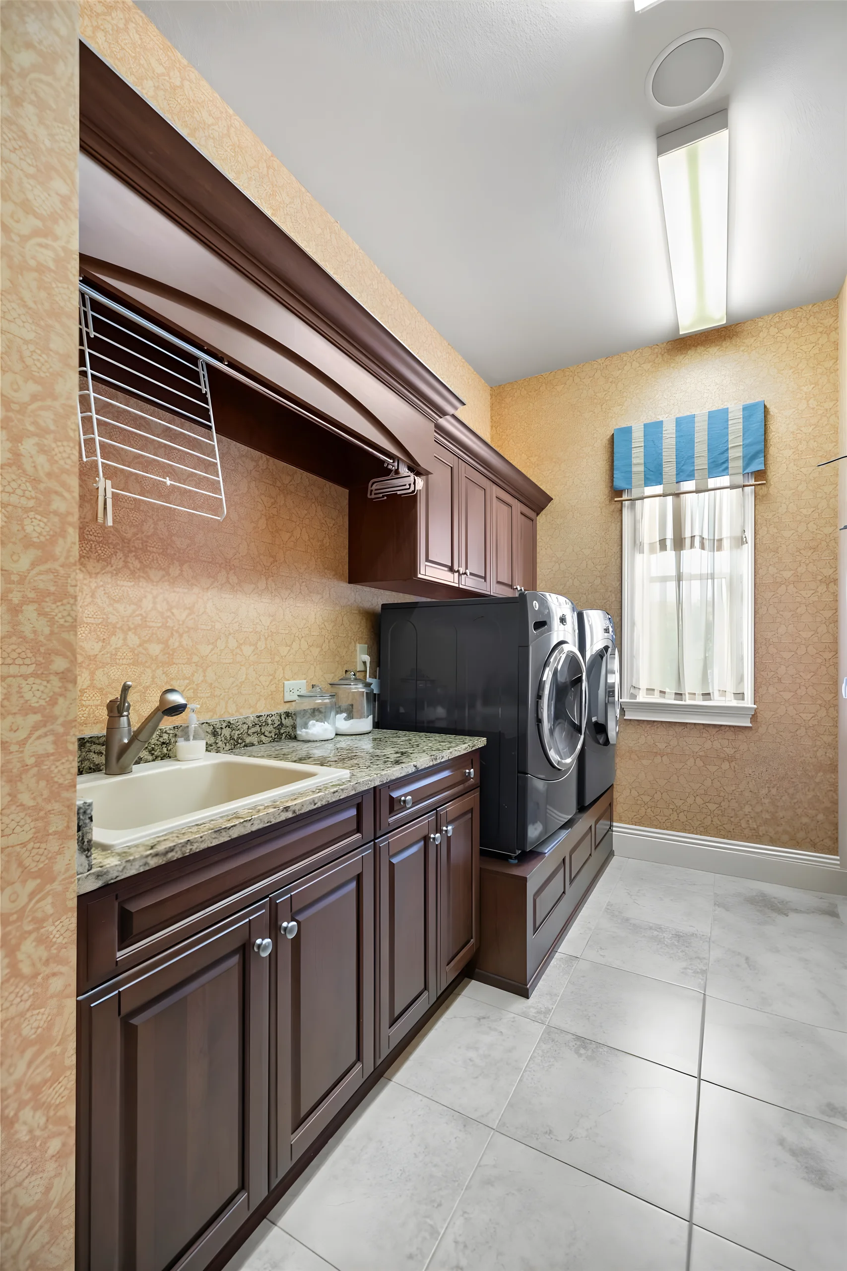 Laundry room with wood cabinets, a utility sink, a granite counter and a front-loading washer and dryer