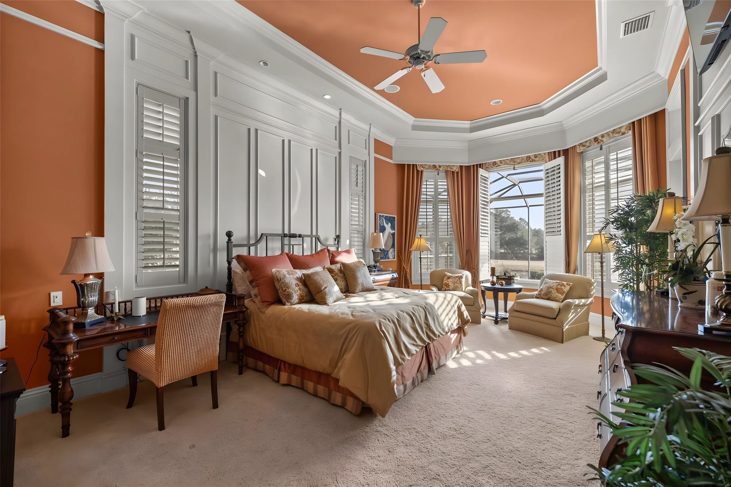 Master bedroom with a tray ceiling, plantation shutters and a bay window onto the lanai and the pond