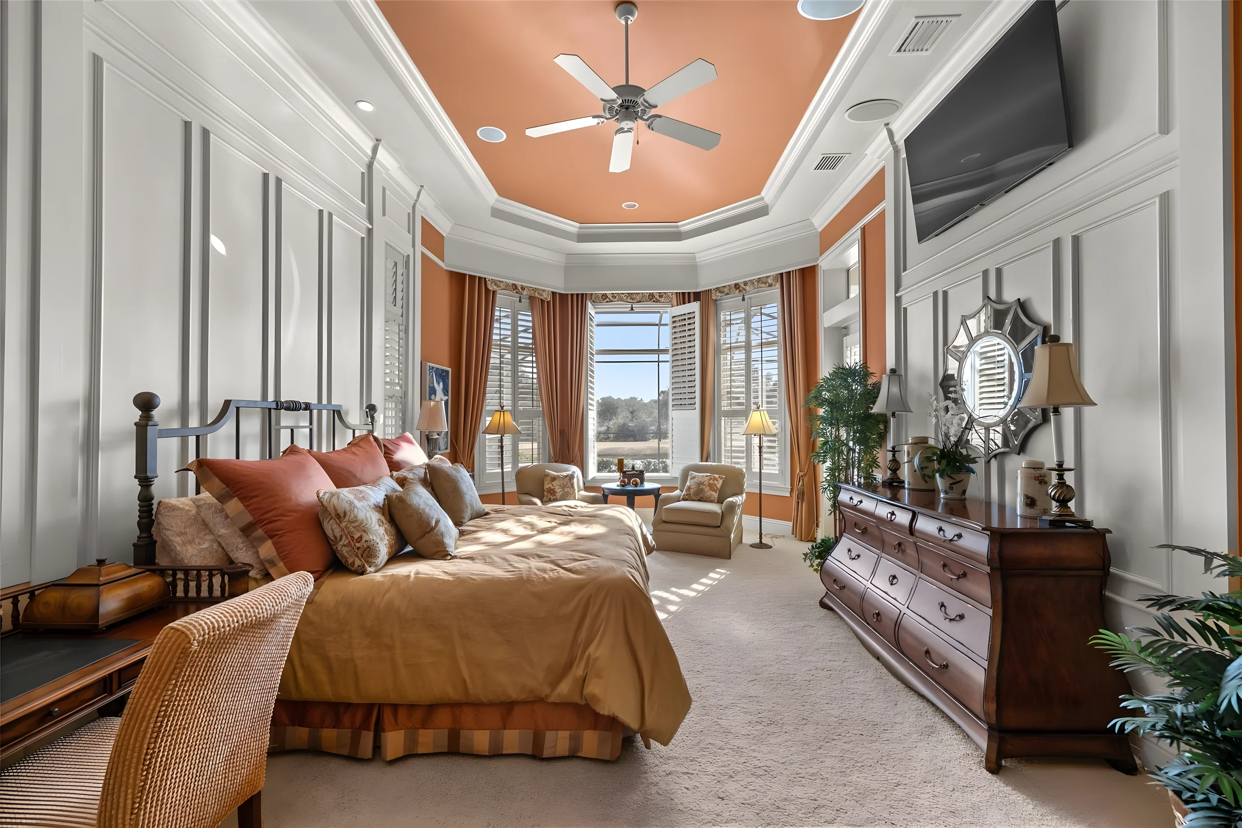 Master bedroom with the bay window sitting area, paneled walls and a wall-mounted TV
