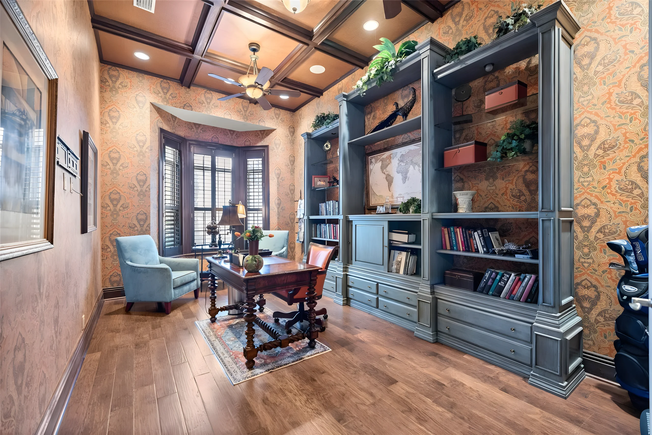 Office with a coffered wood ceiling, built-in bookcases and a bay window with plantation shutters
