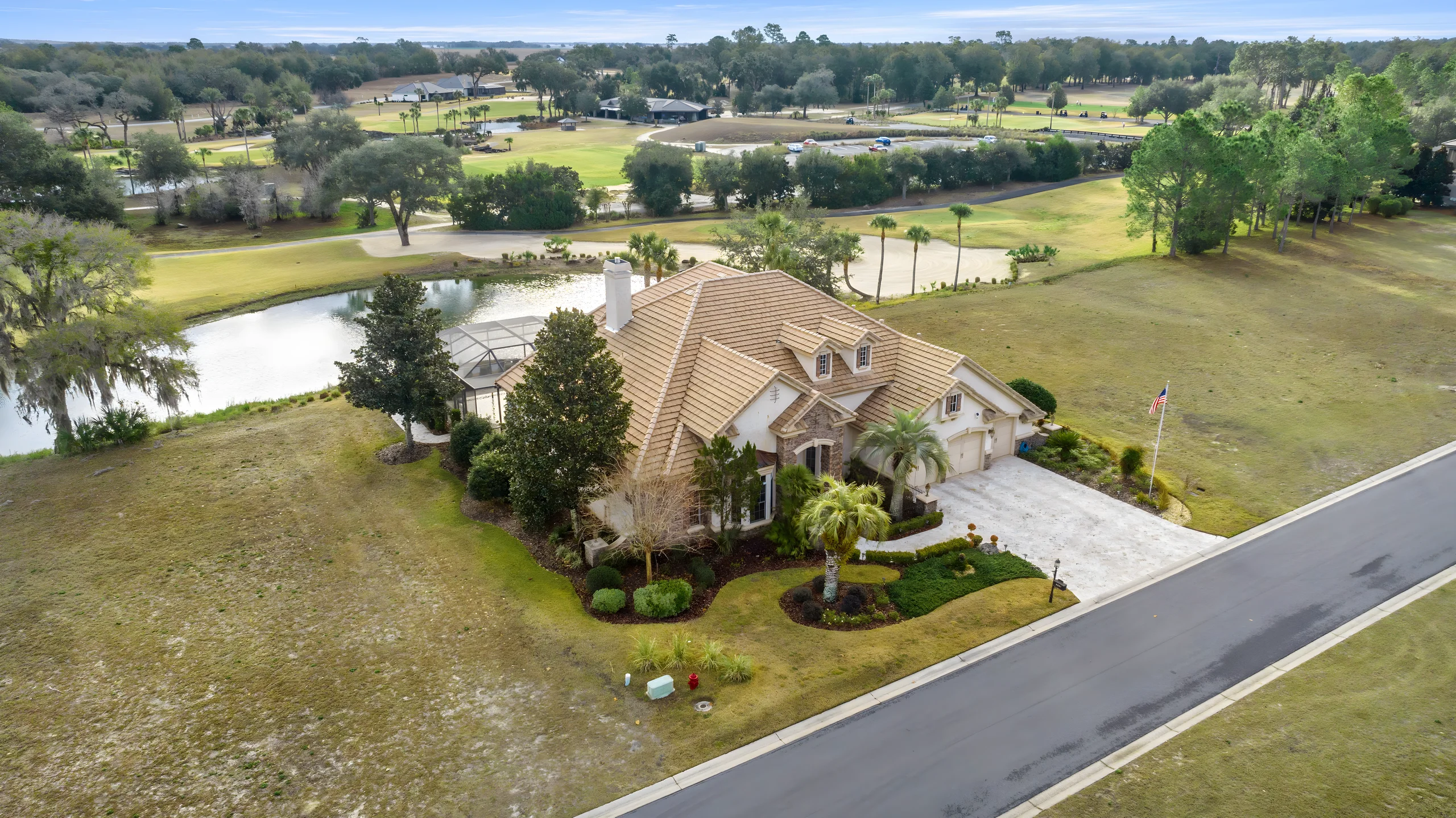Aerial view of the house on its lot, with the pond and the golf course behind it